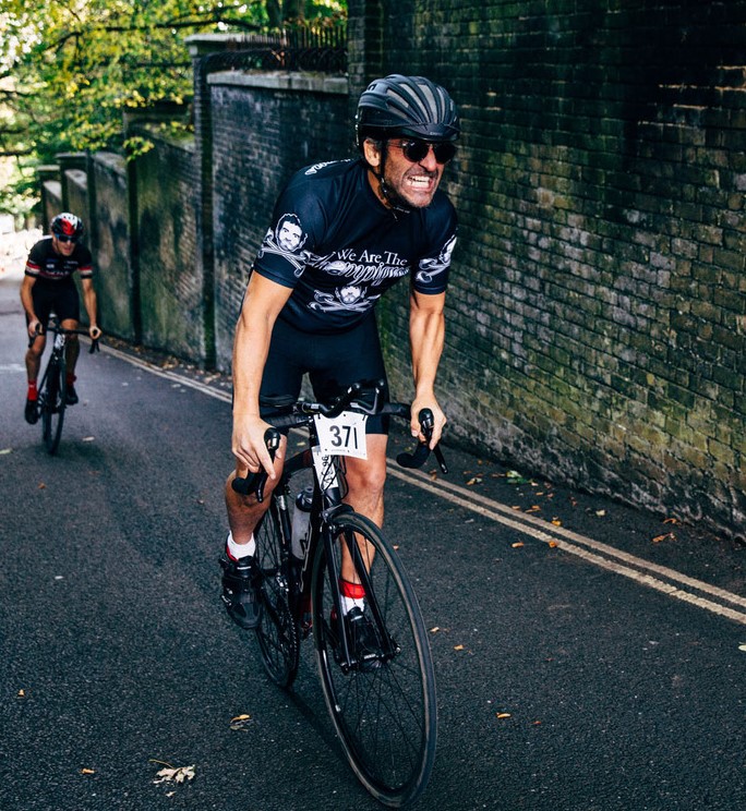 Bowel cancer patient Dick Carruthers during uphill section of a cycle race. Dressed in black helmet and black cycling jersey and shorts