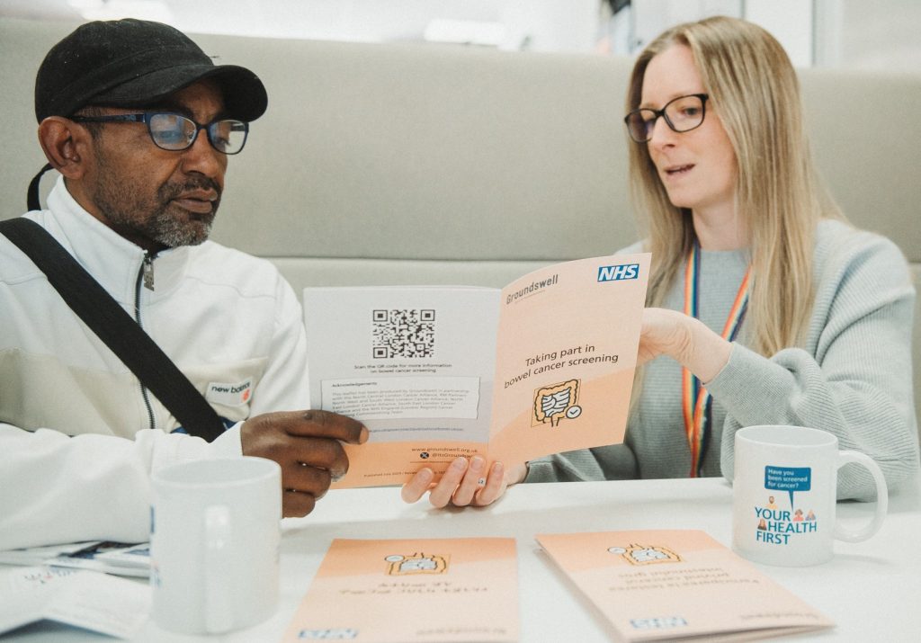 Manager for homelessness support service shows bowel screening booklet to a service user.