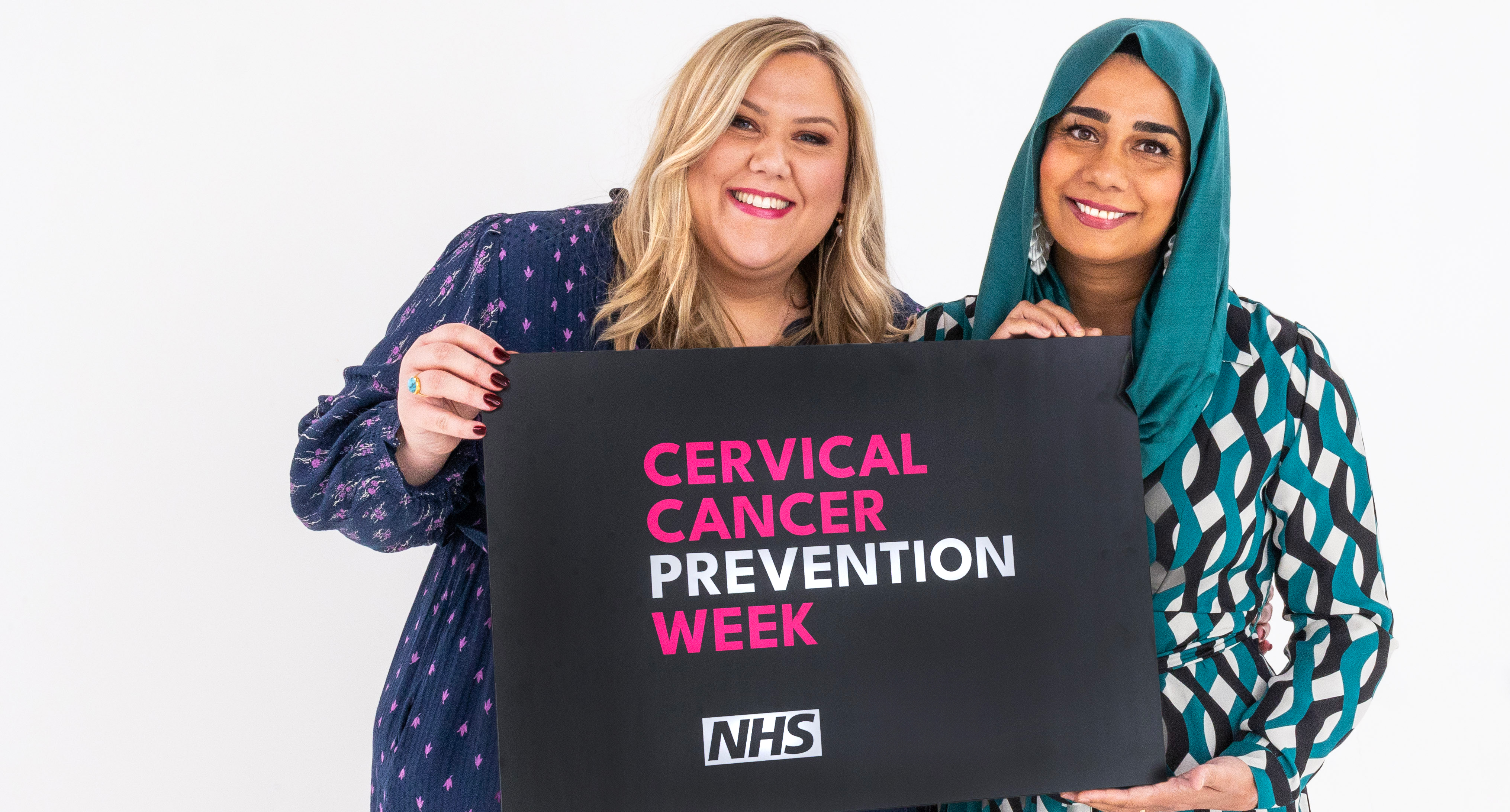 Laura Adlington (left) and Dr Nighat Arif stand together holding a banner between them. It says Cervical Cancer Prevention Week and includes the NHS logo.