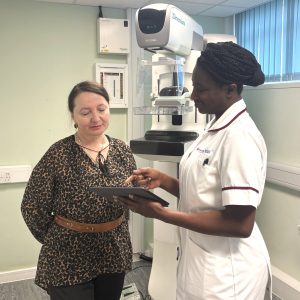 A nurse points to an iPad to explain breast cancer screening to a patient in her native language.