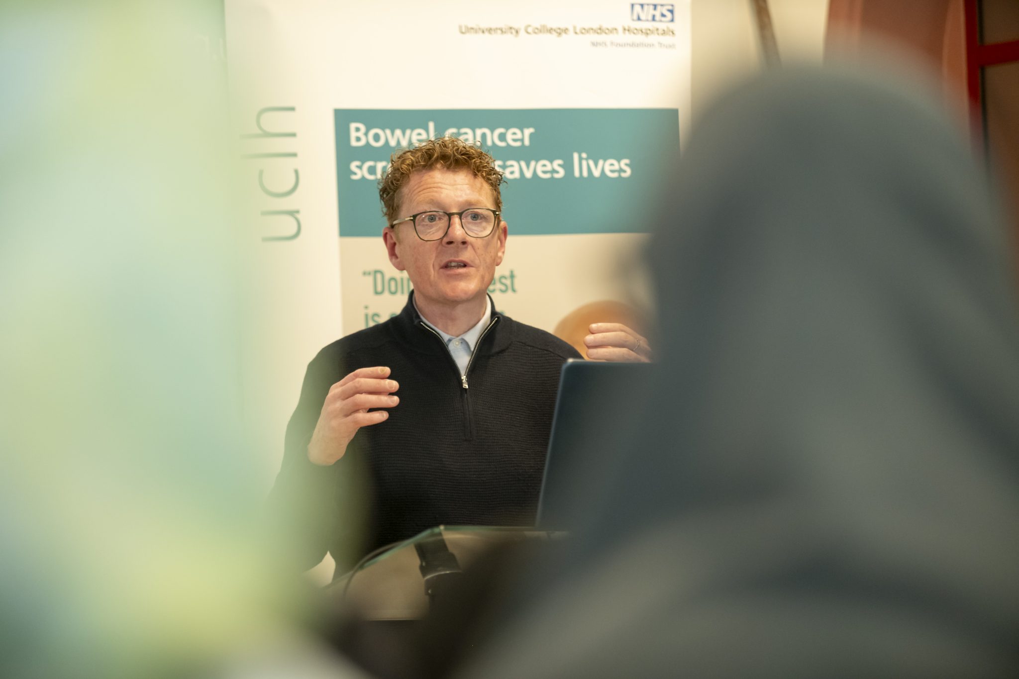 A healthcare professional addressing an audience on bowel cancer screening.