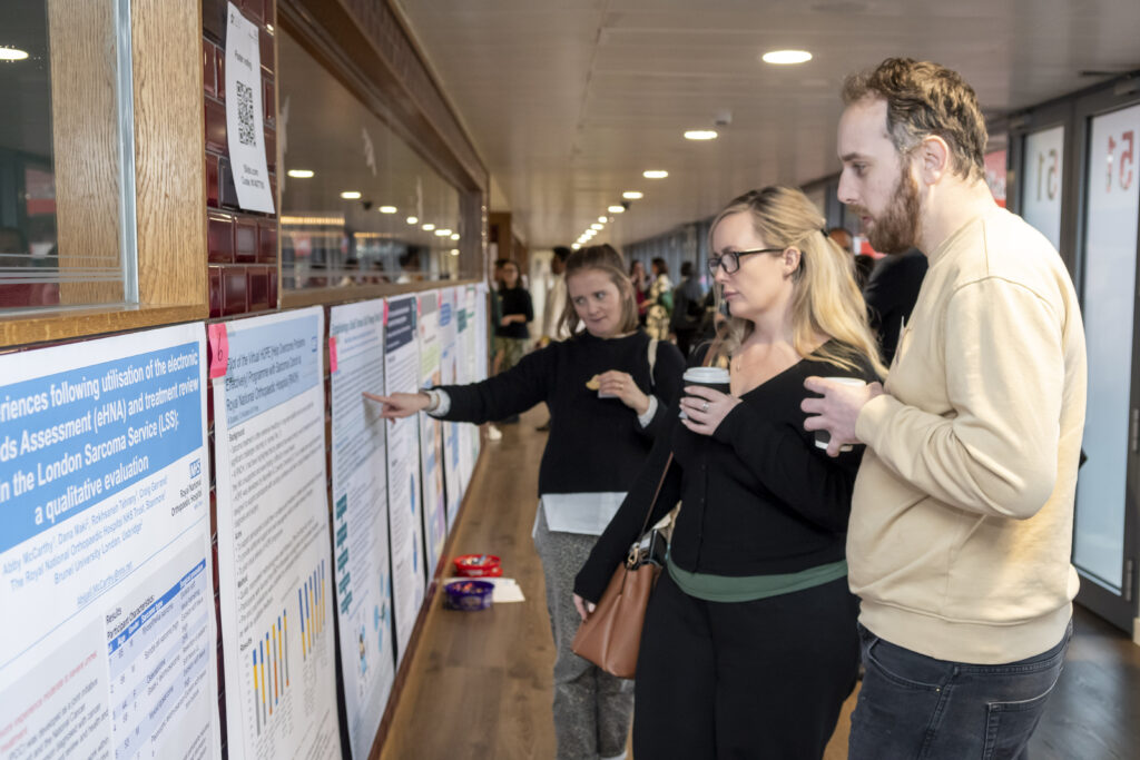 People viewing a wall of academic posters at a conference