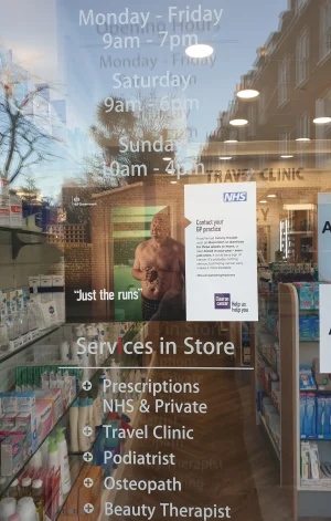 Glass entrance door to a pharmacy listing the services provided inside